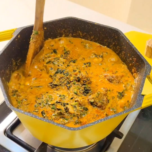 Bowl of egusi soup with visible pieces of Beem Farms smoky goat. Bowl of egusi soup with visible pieces of smoky goat.